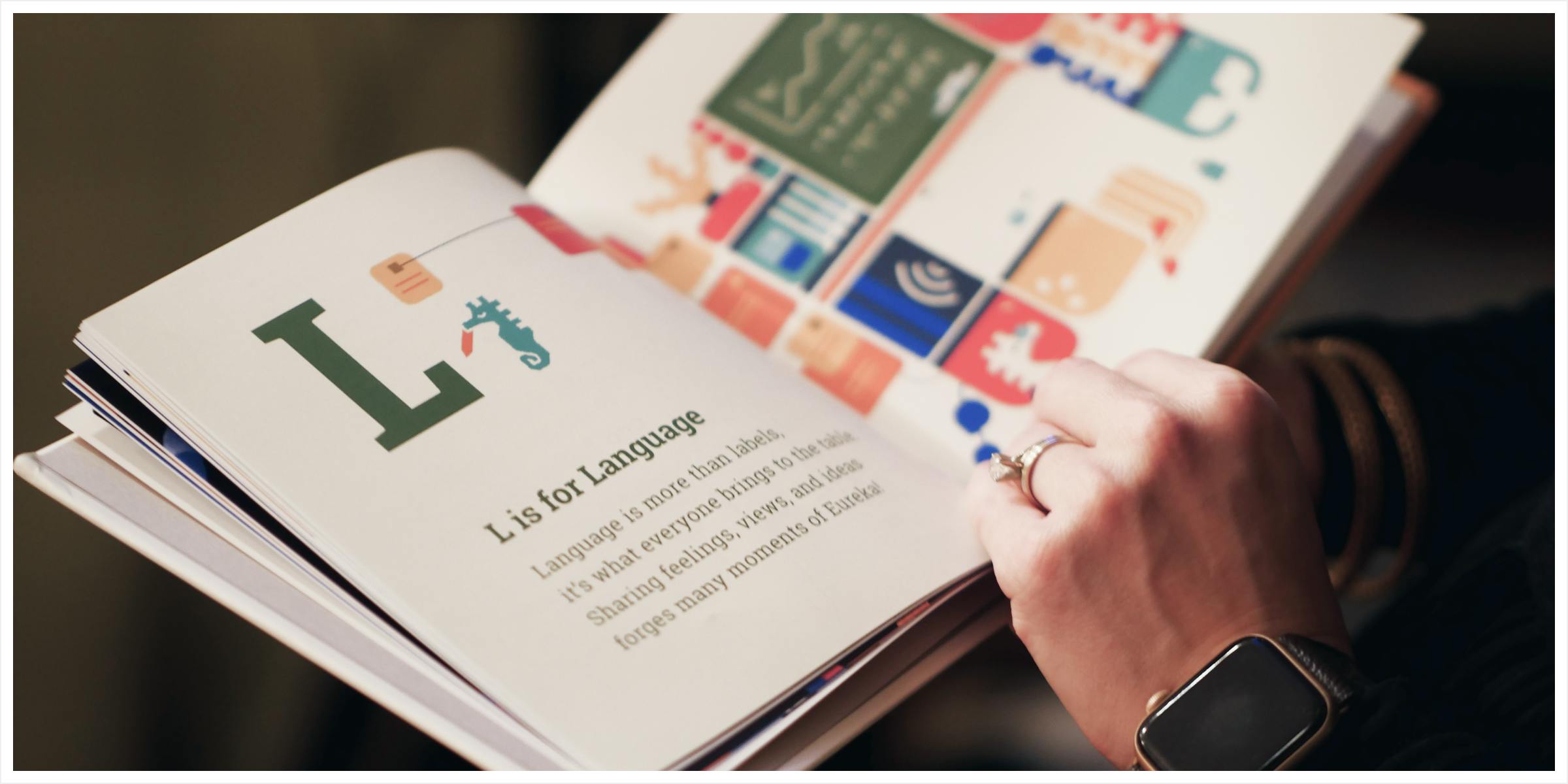 A book being held. The page says L is for language
