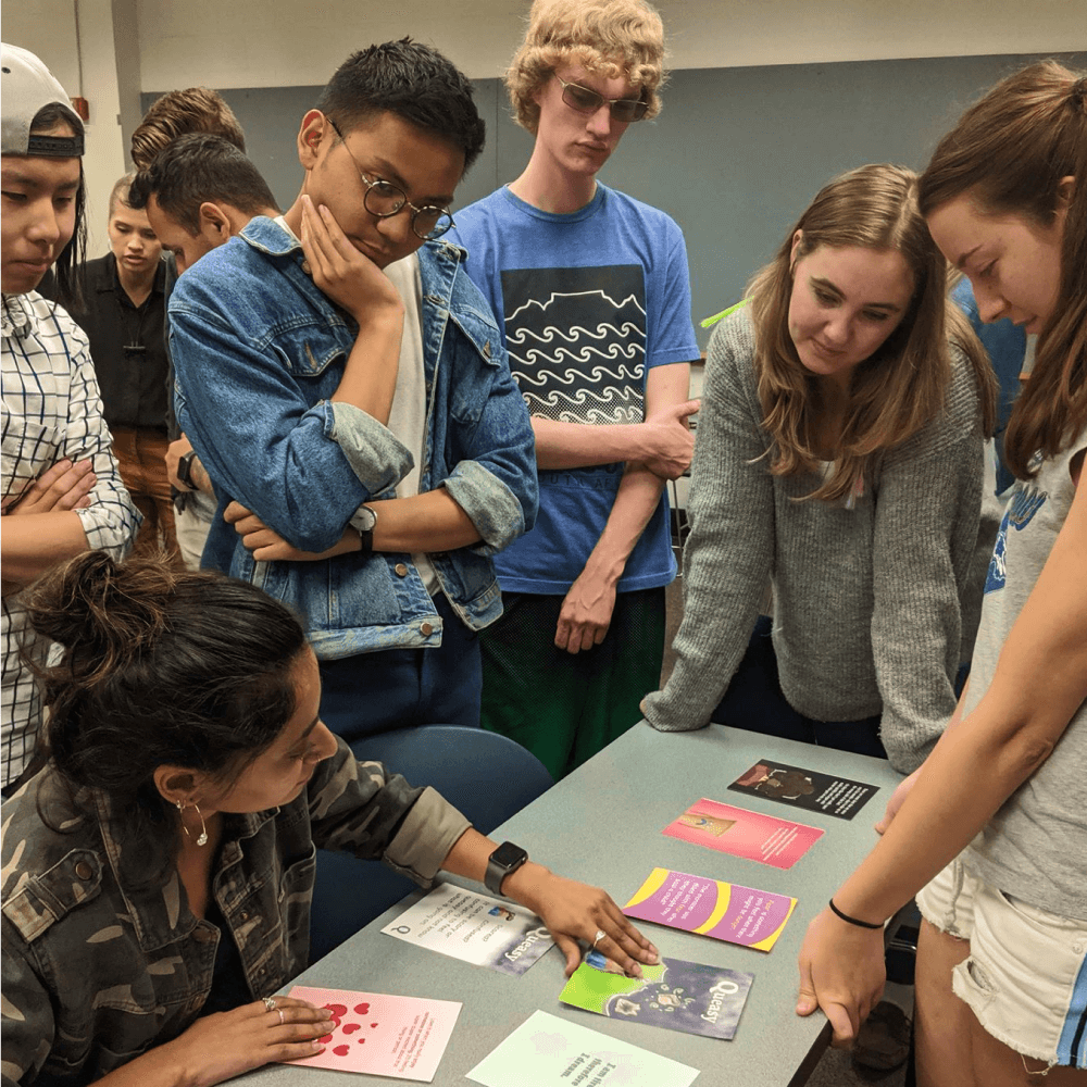 Group standing around table reviewing cards
