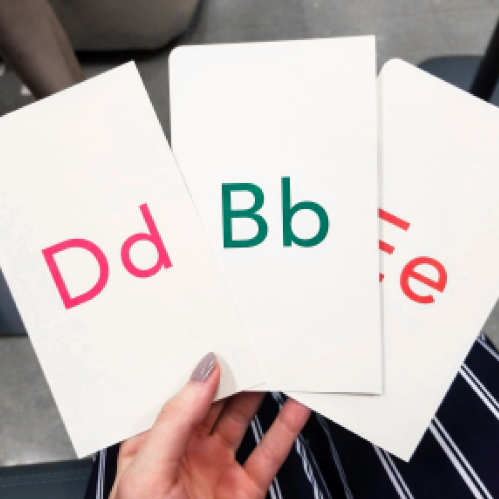 Hand holding cards with letters B, D, and E