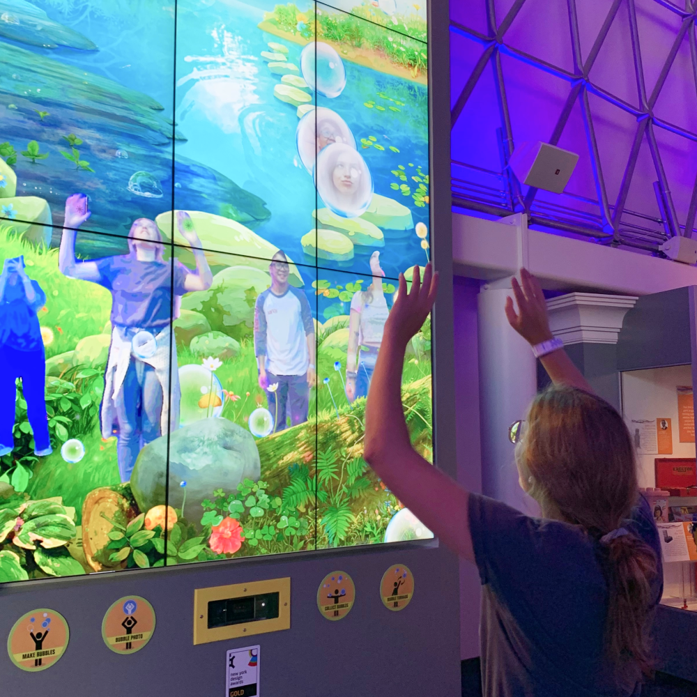 Team member playing with interactive bubble display
